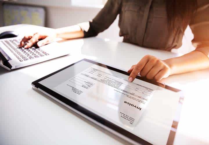 Person reading from tablet and typing into laptop